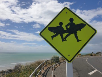 Zwei Kinder, die je ein Surfboard tragen